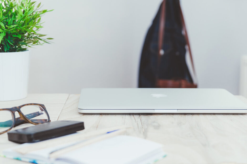 メガネやペンケースや観葉植物が置かれたおしゃれなテーブルで、MacBookでブログ・WEBマガジン・アフィリエイトサイト・WEBサイトの記事執筆やデザインをおこなう光景