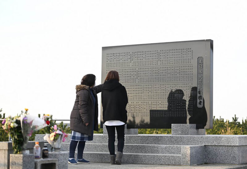 2022年3月11日午前6時30分過ぎ、宮城県仙台市若林区にある慰霊碑に刻まれた名前を指さす女性たち